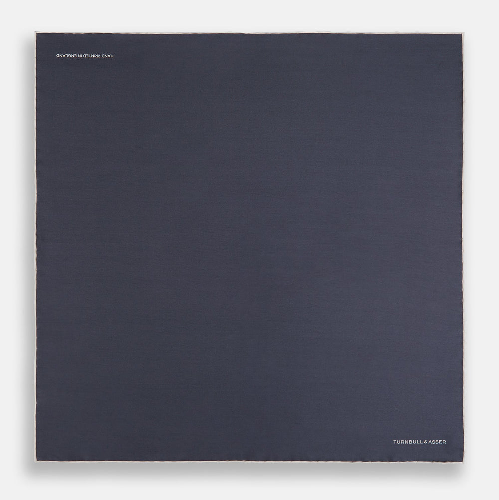 A neatly folded grey silk pocket square with ecru piping—ideal for formal wear—and TURNBULL & ASSER printed in white in one corner.