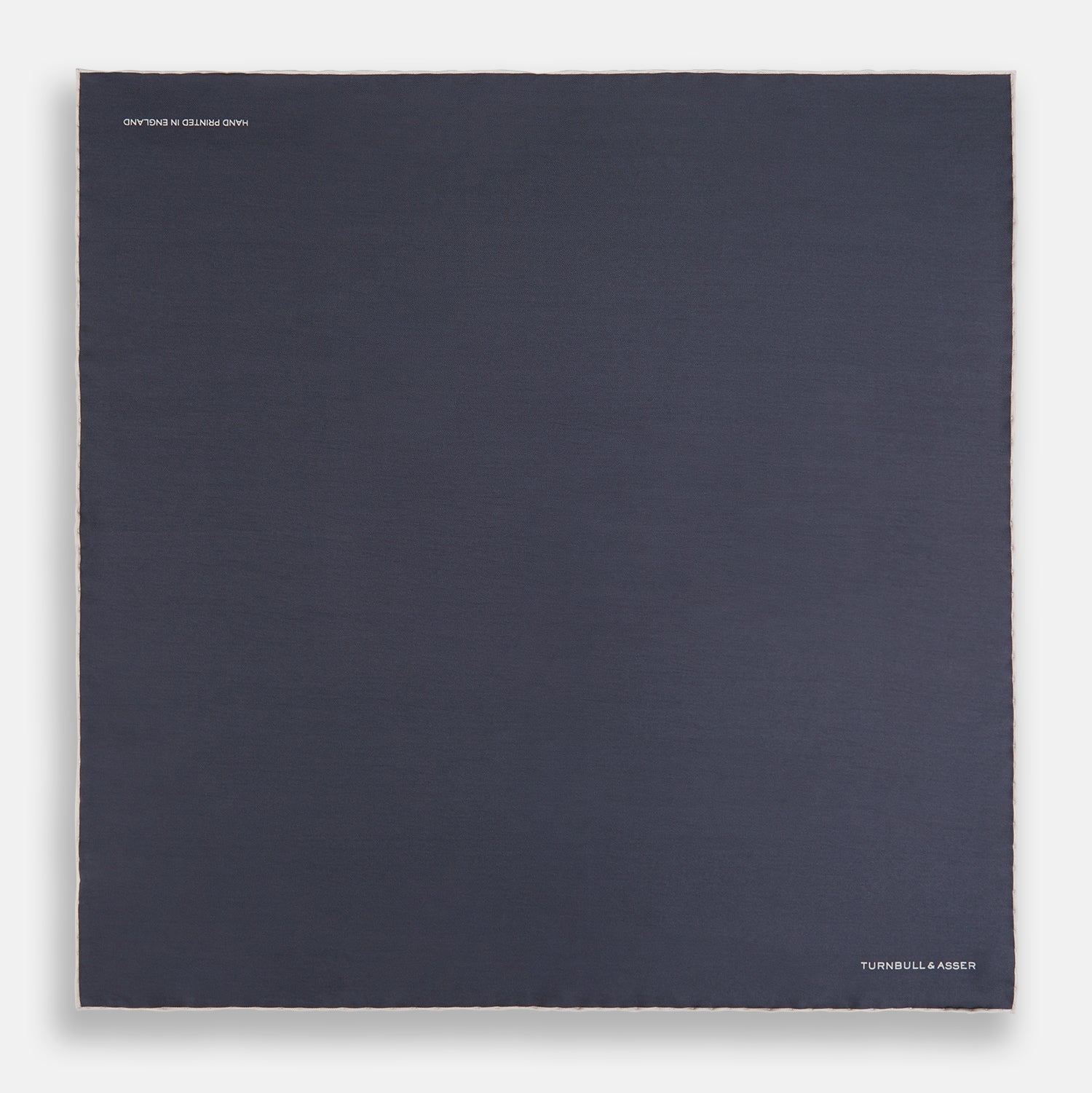 View 4 of product A neatly folded grey silk pocket square with ecru piping—ideal for formal wear—and TURNBULL & ASSER printed in white in one corner.