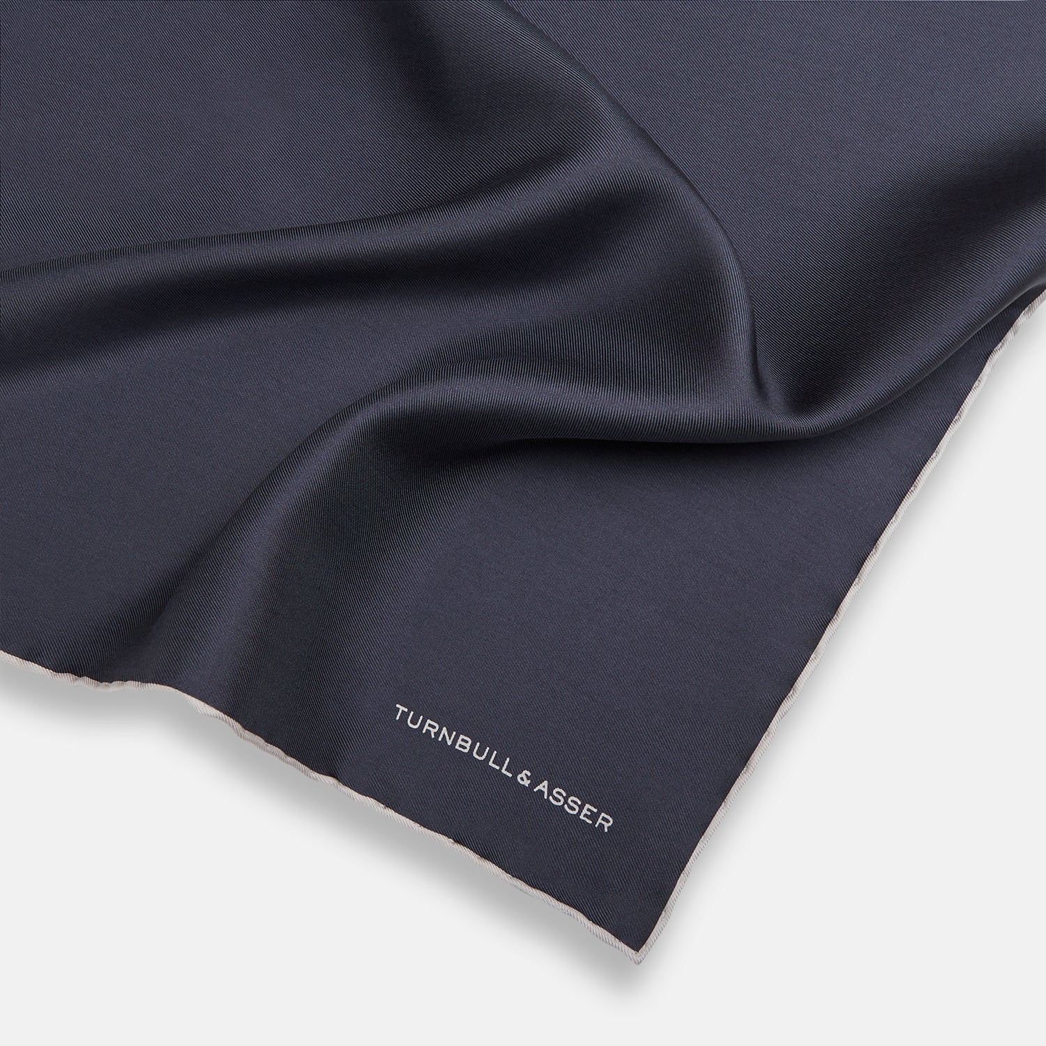 View 2 of product A neatly folded grey silk pocket square with ecru piping—ideal for formal wear—and TURNBULL & ASSER printed in white in one corner.
