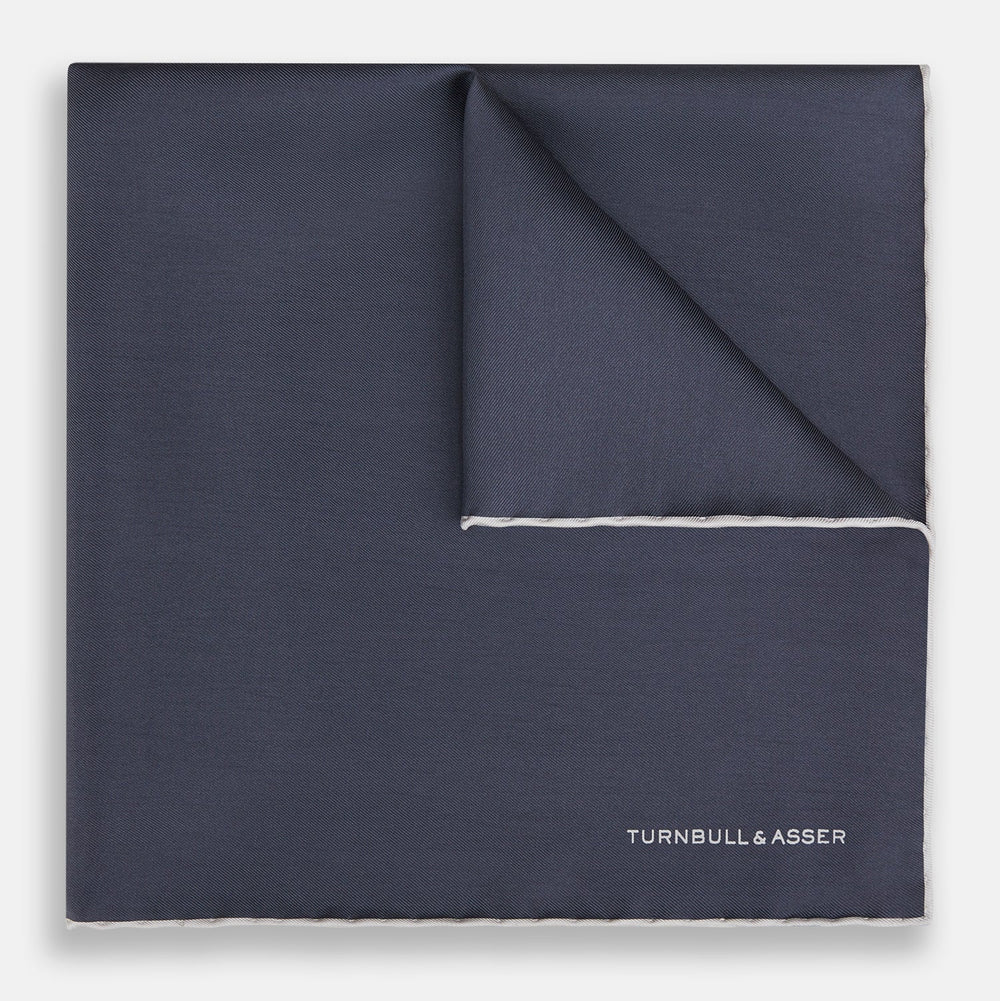 A neatly folded grey silk pocket square with ecru piping—ideal for formal wear—and TURNBULL & ASSER printed in white in one corner.