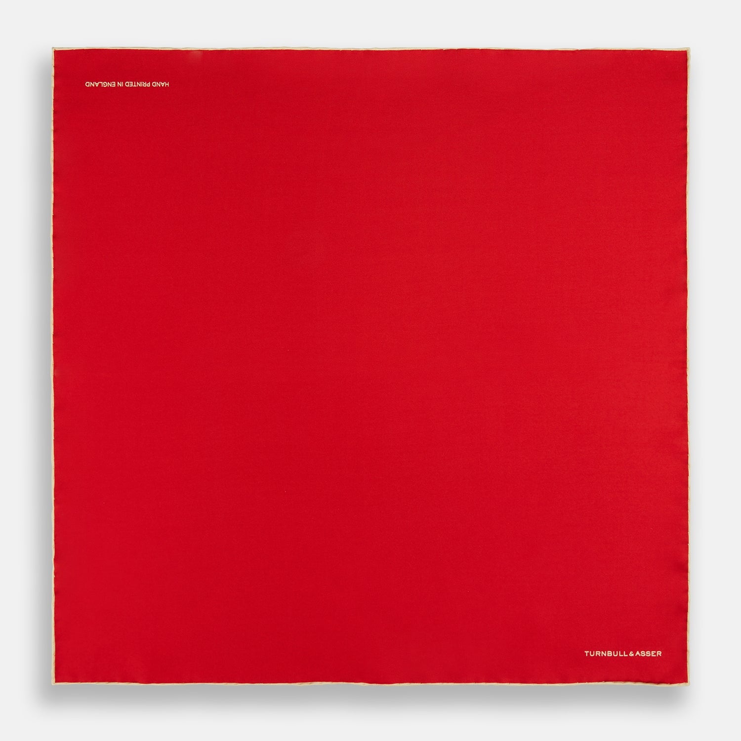 View 4 of product The Turnbull & Asser RED AND GOLD PIPED SILK POCKET SQUARE is a vibrant red silk accessory with gold edging and the brand’s logo in white on the bottom right—ideal for elevating formal looks.