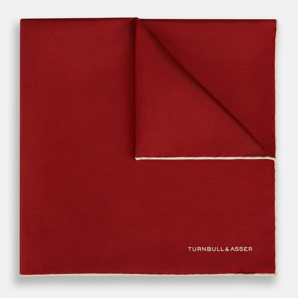 The Turnbull & Asser Burgundy and Ecru Piped Silk Pocket Square features a classic square design, contrasting ecru piping on the edge, and white branding in the lower corner—a refined accessory for formal looks.