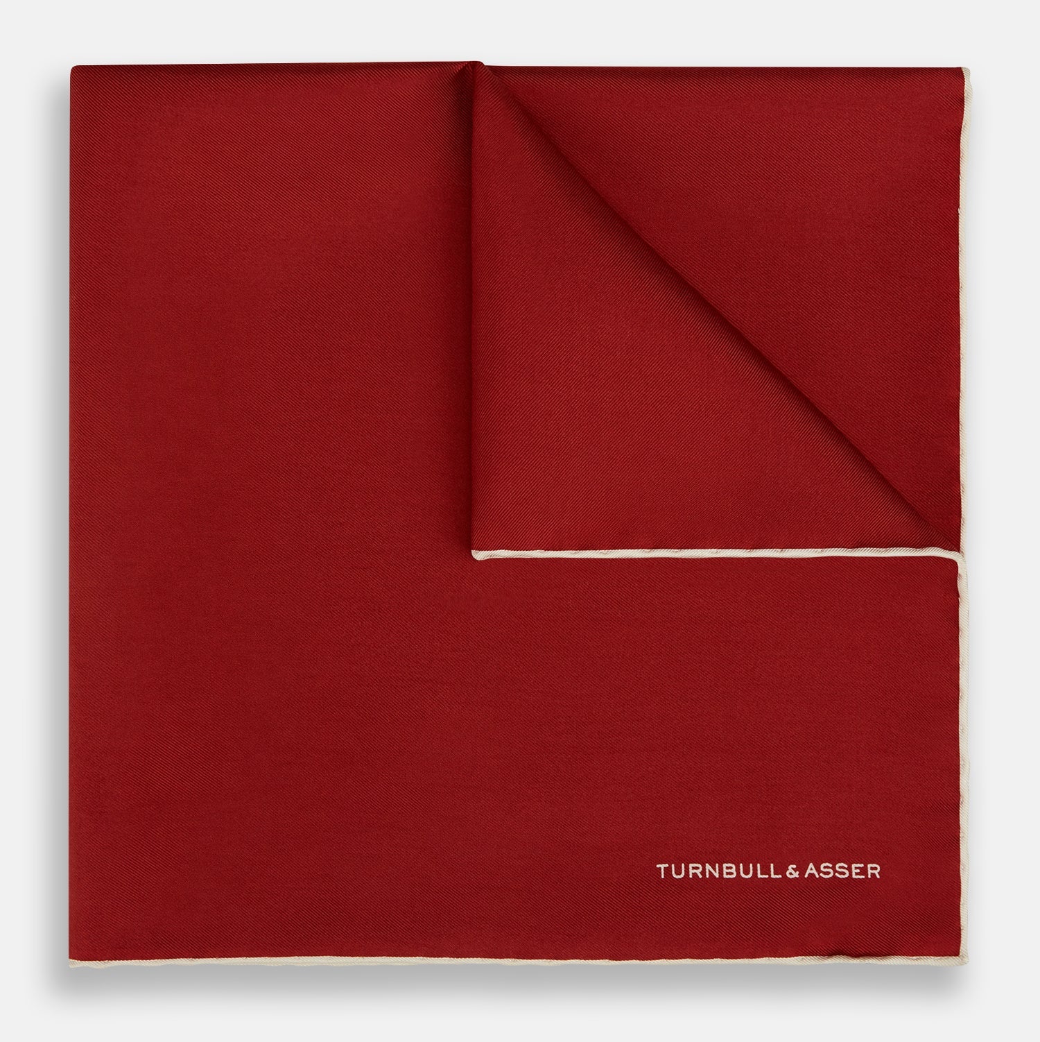View 1 of product The Turnbull & Asser Burgundy and Ecru Piped Silk Pocket Square features a classic square design, contrasting ecru piping on the edge, and white branding in the lower corner—a refined accessory for formal looks.