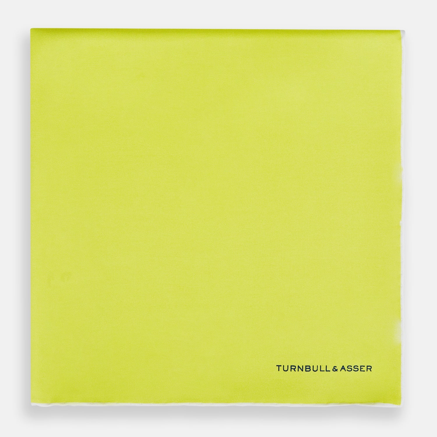 View 3 of product The Canary Yellow Piped Silk Pocket Square by Turnbull & Asser features white edges and black branding in the bottom right corner, making it a perfect accessory for formal attire. Shown on a plain white background.