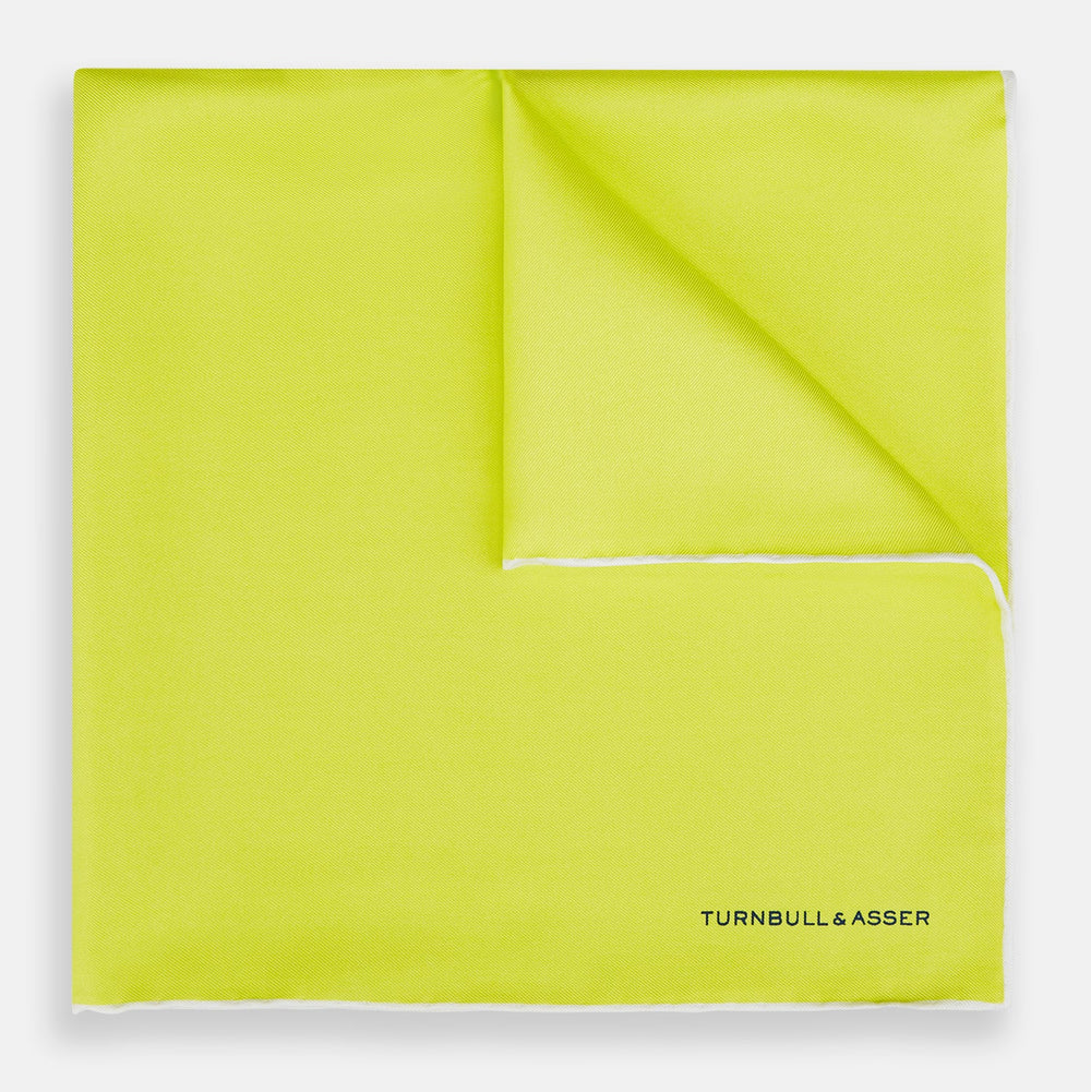 The Canary Yellow Piped Silk Pocket Square by Turnbull & Asser features white edges and black branding in the bottom right corner, making it a perfect accessory for formal attire. Shown on a plain white background.