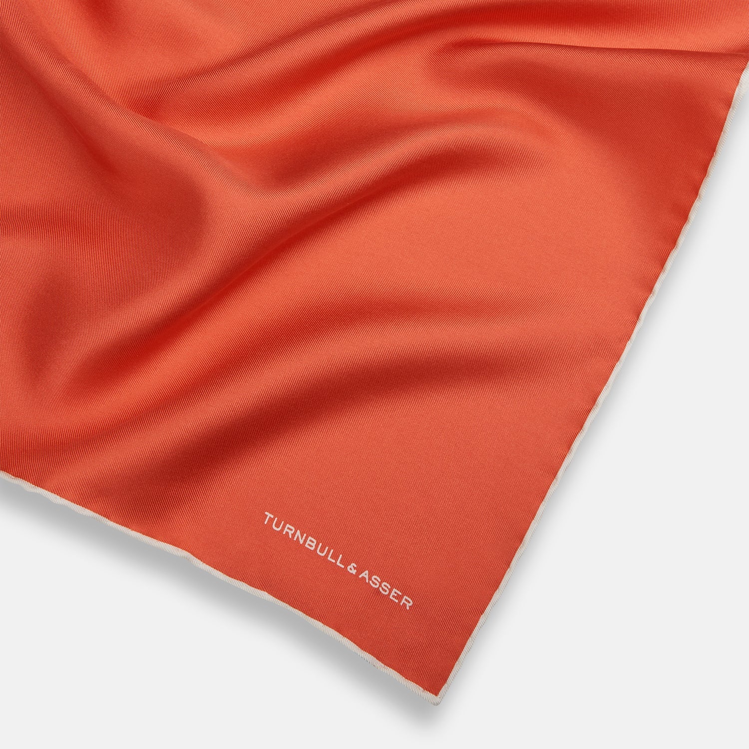 View 2 of product The Orange and White Piped Silk Pocket Square by Turnbull & Asser features a solid orange design with white piping and the brand’s logo in the bottom right corner, making it an elegant addition to any formal outfit.