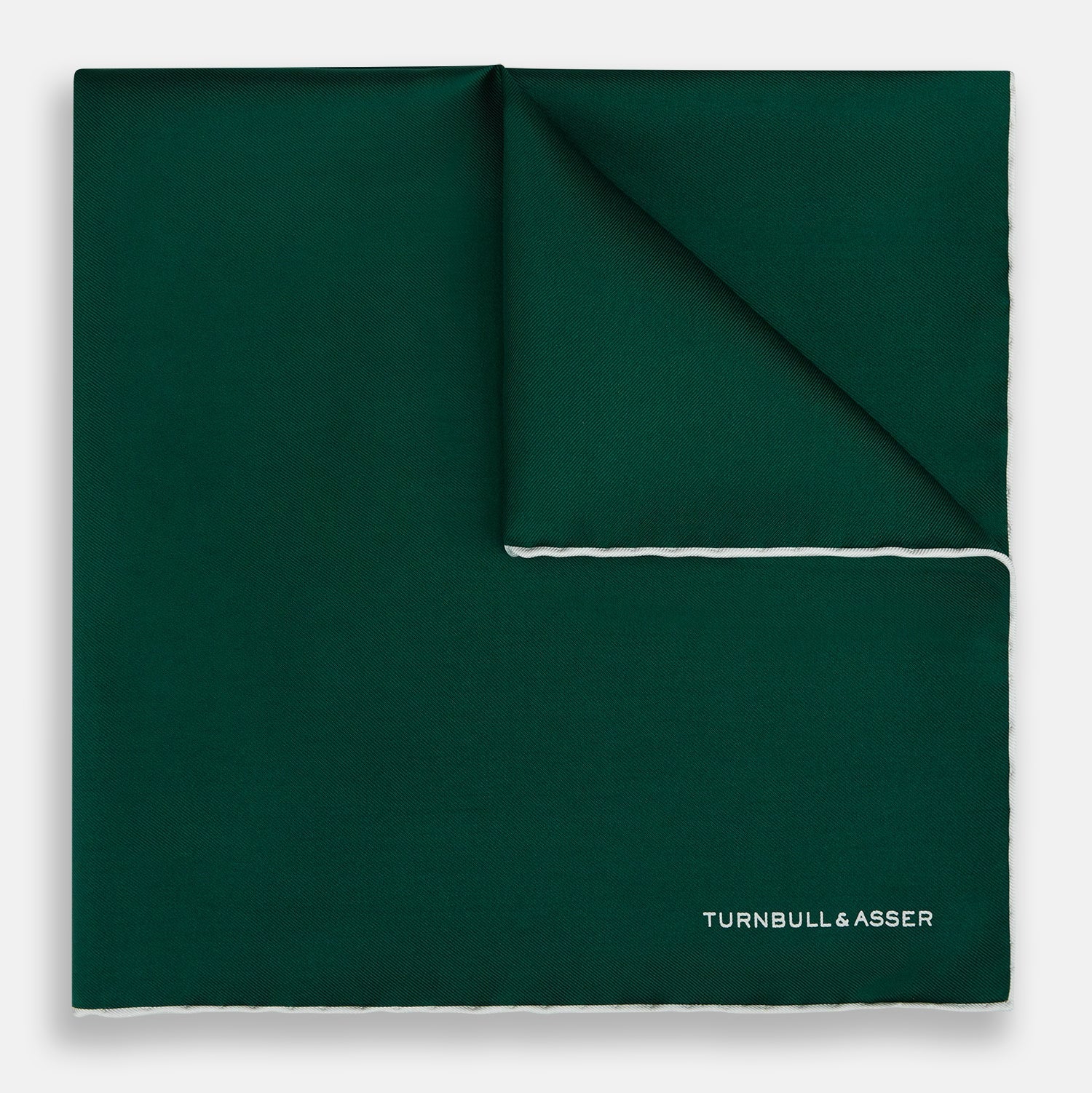 View 1 of product The FOREST GREEN AND ECRU PIPED SILK POCKET SQUARE by Turnbull & Asser features forest green silk with ecru piping, neatly folded to display both sides, and the brand name printed in white in the lower right corner—ideal for formal attire.
