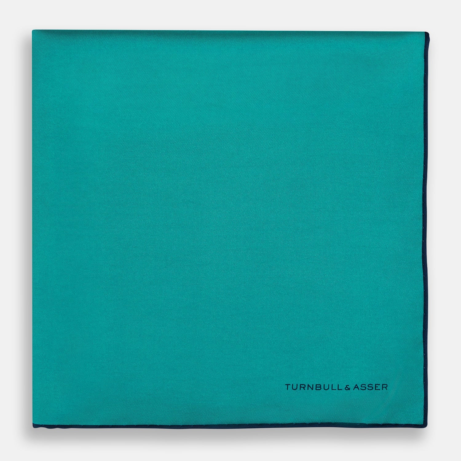 View 3 of product The Turquoise Piped Silk Pocket Square by Turnbull & Asser features dark blue edging and the brand’s logo, offering a sophisticated accent to formal outfits.