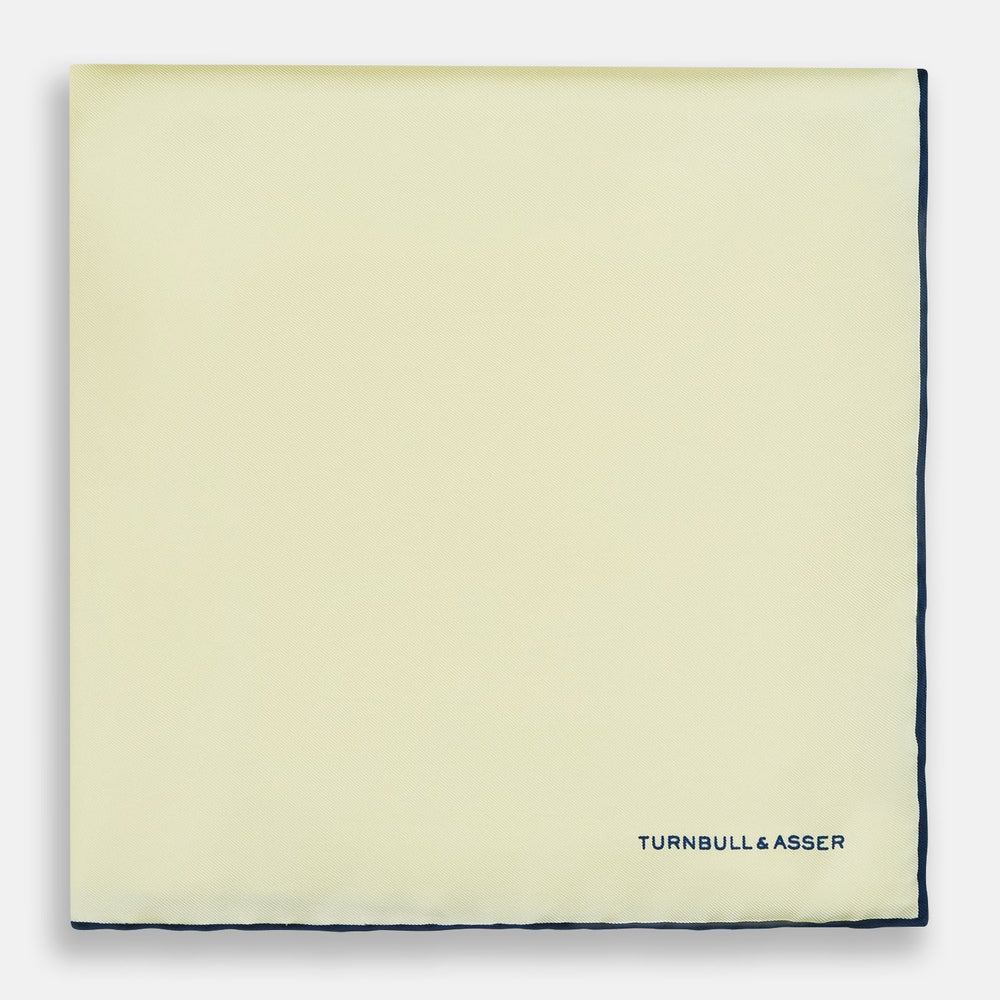 The Turnbull & Asser GOLD AND NAVY BLUE PIPED SILK POCKET SQUARE features navy piping and an embroidered logo—a refined accessory to elevate any formal look.