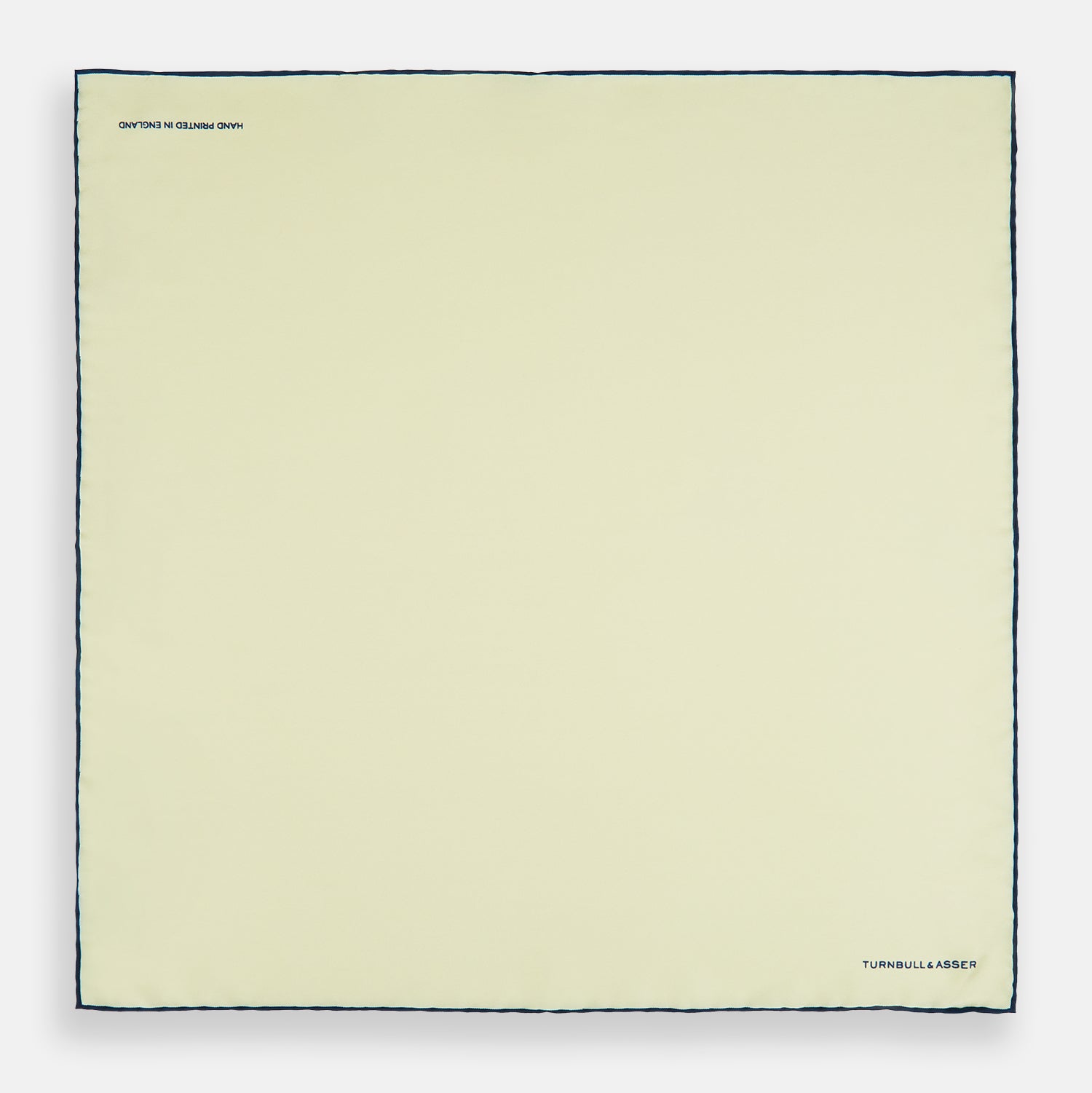 View 4 of product The Turnbull & Asser GOLD AND NAVY BLUE PIPED SILK POCKET SQUARE features navy piping and an embroidered logo—a refined accessory to elevate any formal look.