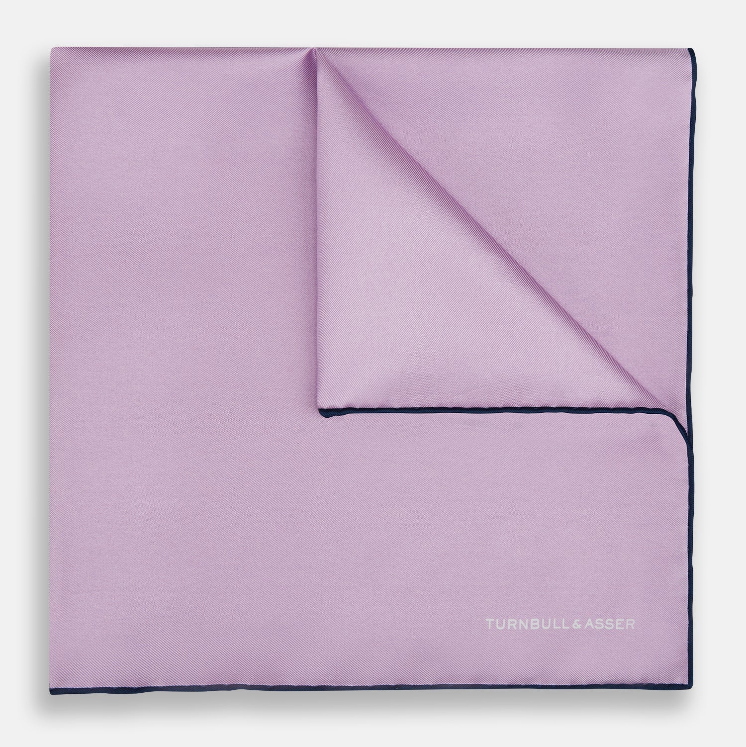 View 1 of product The Turnbull & Asser Lilac Piped Silk Pocket Square features dark edging and a white brand logo in one corner, making it a stylish choice for formal attire. Displayed against a white background.