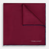 View 1 of product The Mauve Piped Silk Pocket Square by Turnbull & Asser features a dark blue edge and white embroidered logo in the lower right corner, making it ideal for formal occasions. Displayed on a plain white background.