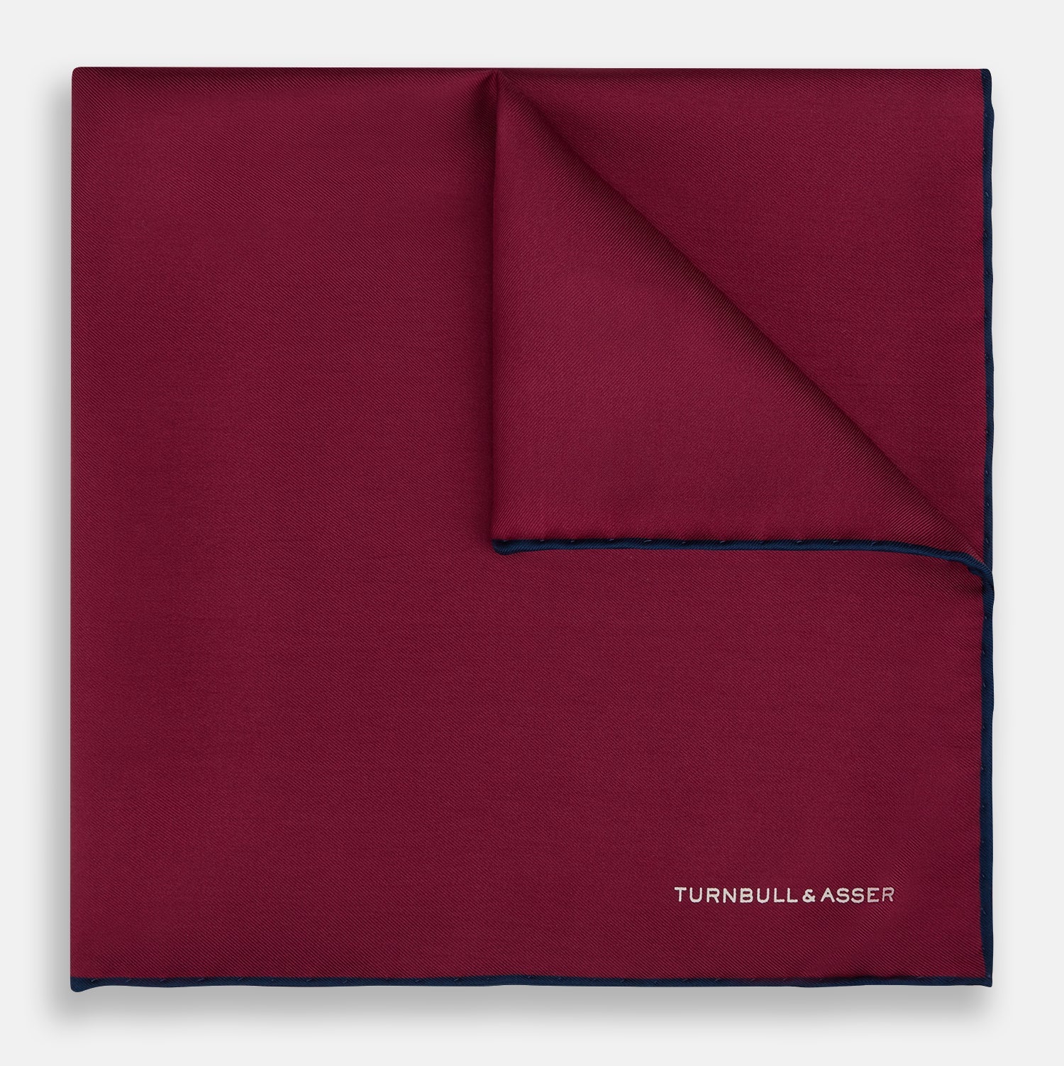 View 1 of product The Mauve Piped Silk Pocket Square by Turnbull & Asser features a dark blue edge and white embroidered logo in the lower right corner, making it ideal for formal occasions. Displayed on a plain white background.