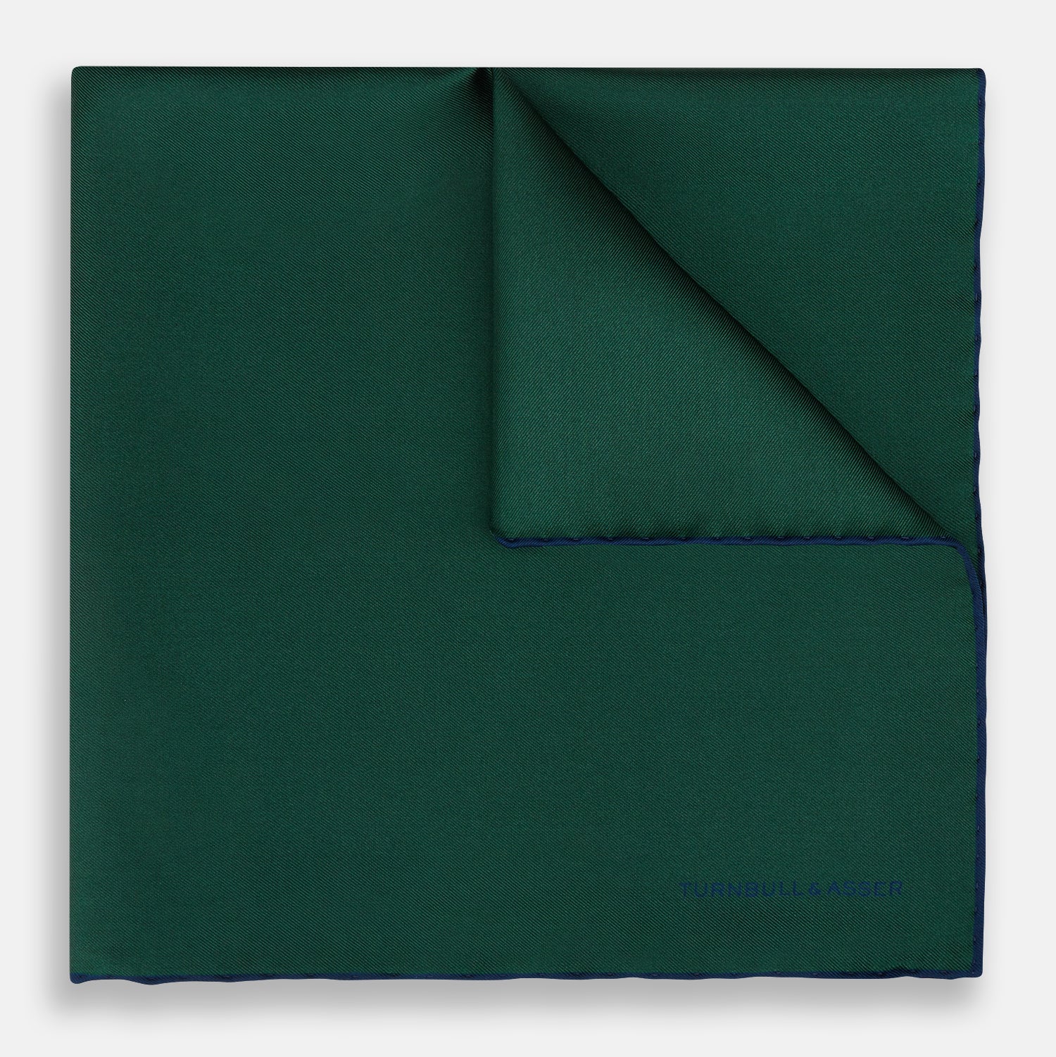 View 1 of product The Turnbull & Asser Petrol Green Piped Silk Pocket Square features a visible stitched edge and a discreet blue logo on the turned-down corner, adding an elegant accent to formal attire.