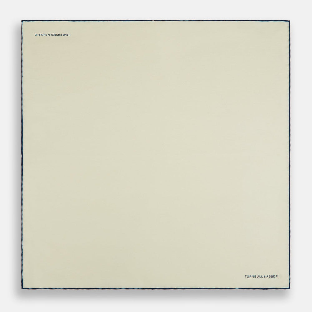 The Ecru and Navy Blue Piped Silk Pocket Square by Turnbull & Asser features contrasting navy piping and finely embroidered branding—an elegant finishing touch to any formal look.