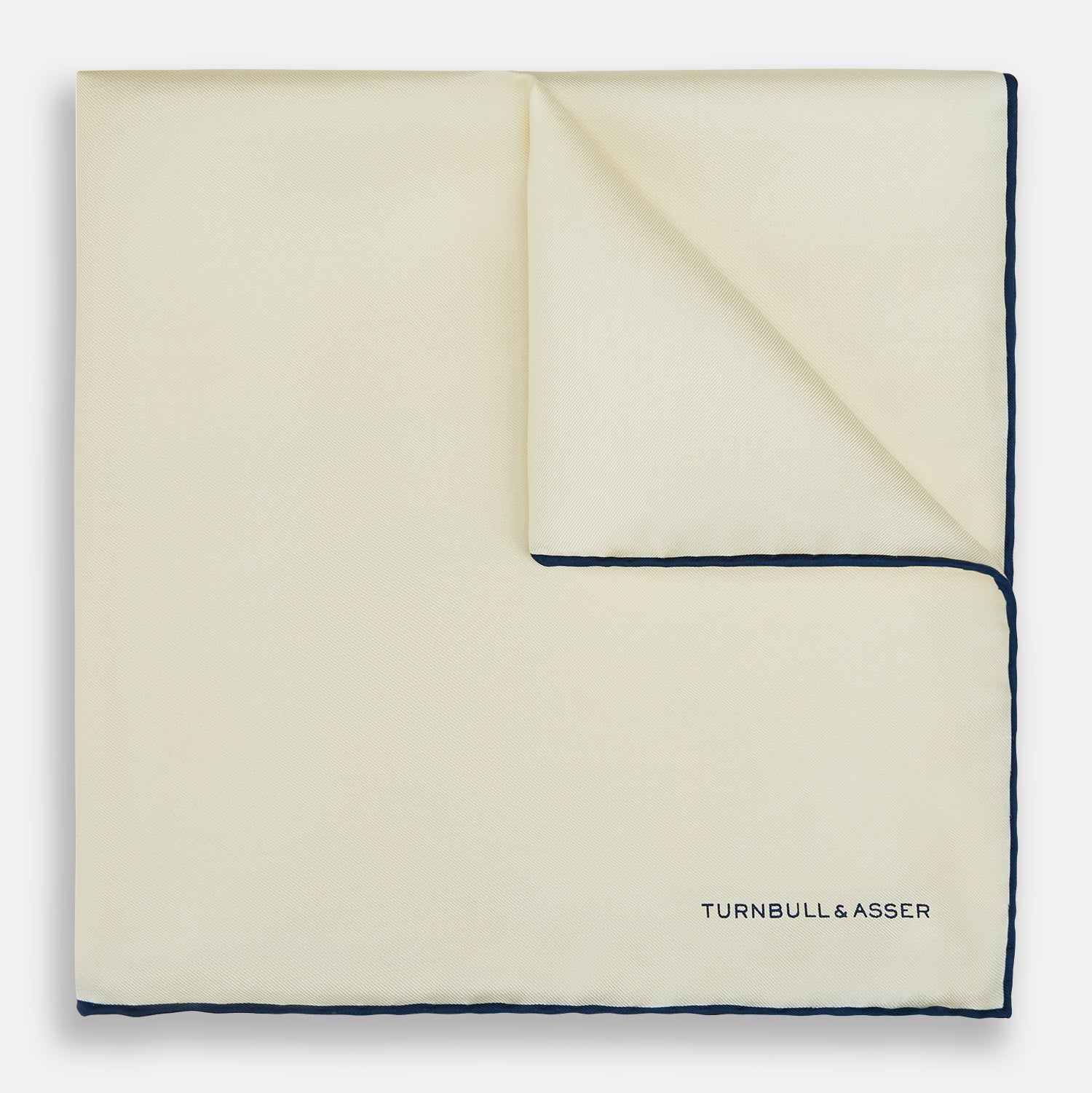 View 1 of product The Ecru and Navy Blue Piped Silk Pocket Square by Turnbull & Asser features contrasting navy piping and finely embroidered branding—an elegant finishing touch to any formal look.