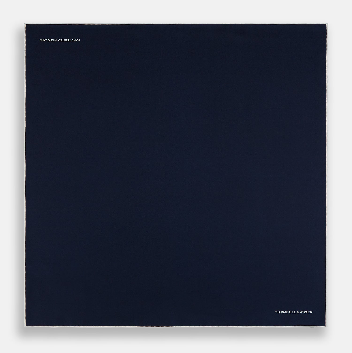 View 4 of product The Midnight Blue Piped Silk Pocket Square from Turnbull & Asser features crisp white trim and subtle branding, making it the ideal accessory to elevate your formal look.