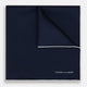 The Midnight Blue Piped Silk Pocket Square from Turnbull & Asser features crisp white trim and subtle branding, making it the ideal accessory to elevate your formal look.