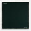View 4 of product The DARK GREEN AND ECRU PIPED SILK POCKET SQUARE by Turnbull & Asser features ecru edging and the brand's logo in one corner, making it a refined choice for formal attire. One corner is folded to show the reverse side.