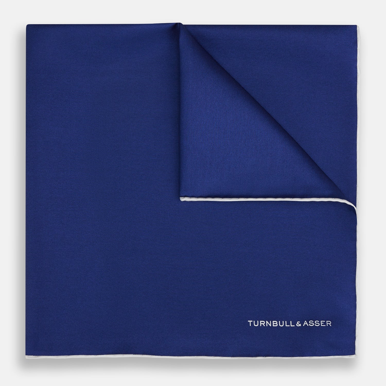 View 1 of product The Turnbull & Asser Royal Blue Piped Silk Pocket Square features white piping and the brand logo embroidered in white at the bottom right, making it perfect for formalwear.