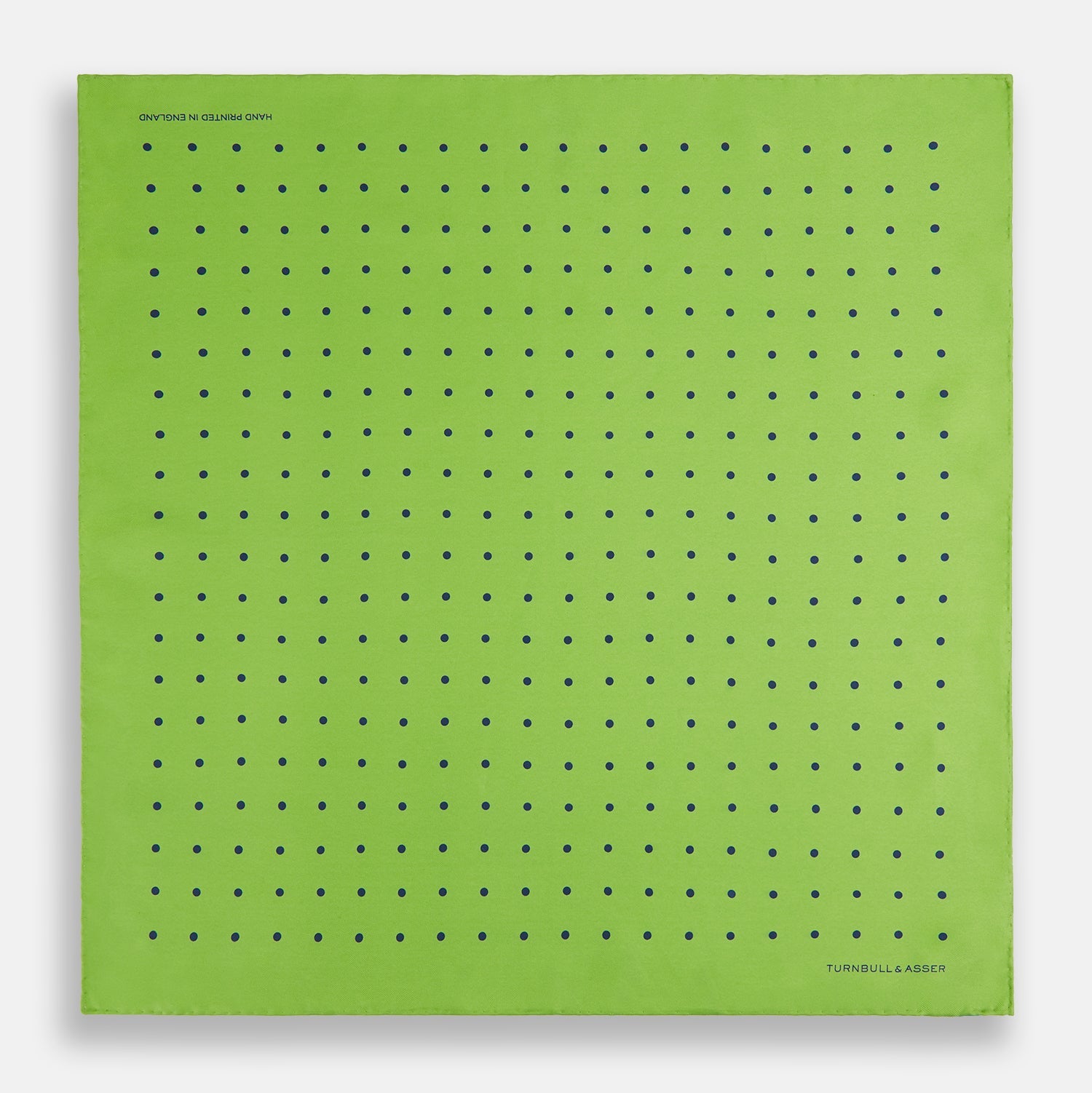 View 4 of product The Turnbull & Asser Lime Green and Blue Spot Silk Pocket Square features evenly spaced blue dots and the brand’s text in the bottom right corner. One corner is folded to reveal the reverse, making it ideal for formal occasions.