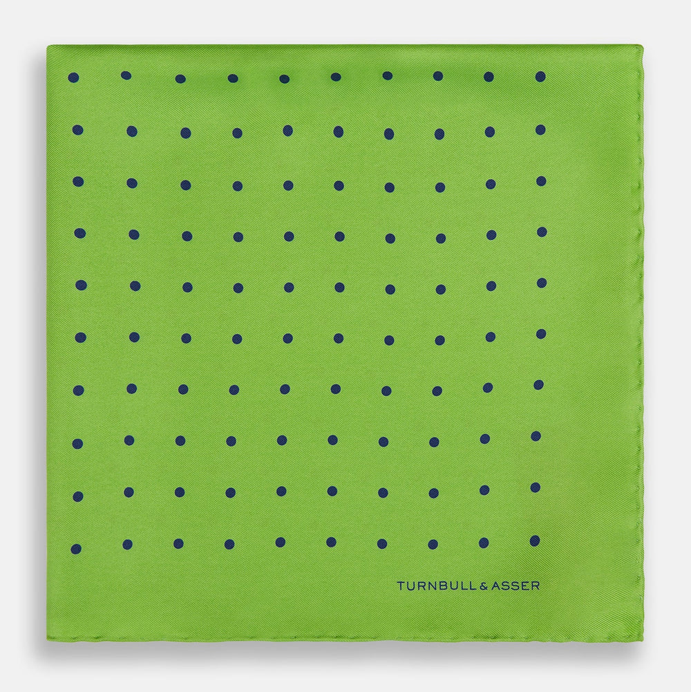 The Turnbull & Asser Lime Green and Blue Spot Silk Pocket Square features evenly spaced blue dots and the brand’s text in the bottom right corner. One corner is folded to reveal the reverse, making it ideal for formal occasions.