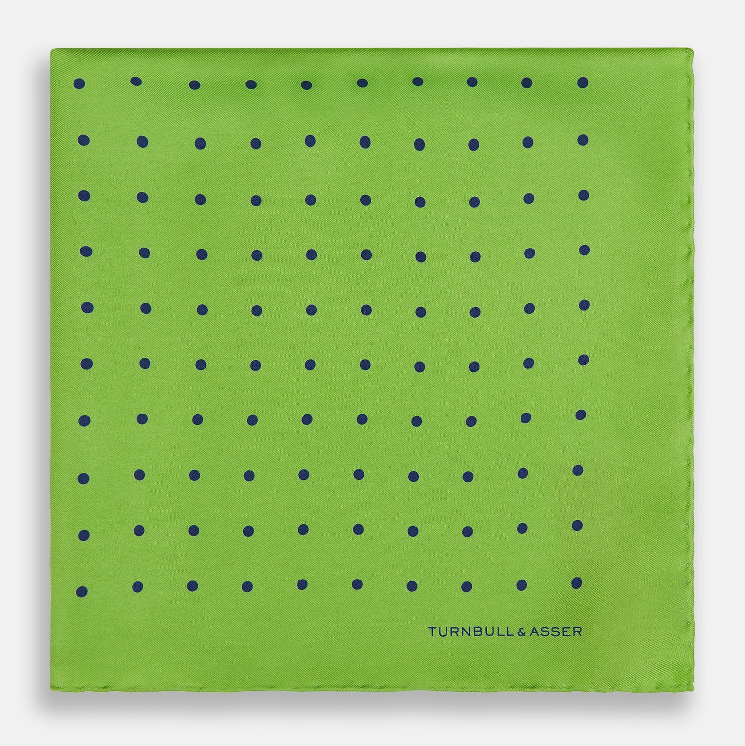 View 3 of product The Turnbull & Asser Lime Green and Blue Spot Silk Pocket Square features evenly spaced blue dots and the brand’s text in the bottom right corner. One corner is folded to reveal the reverse, making it ideal for formal occasions.