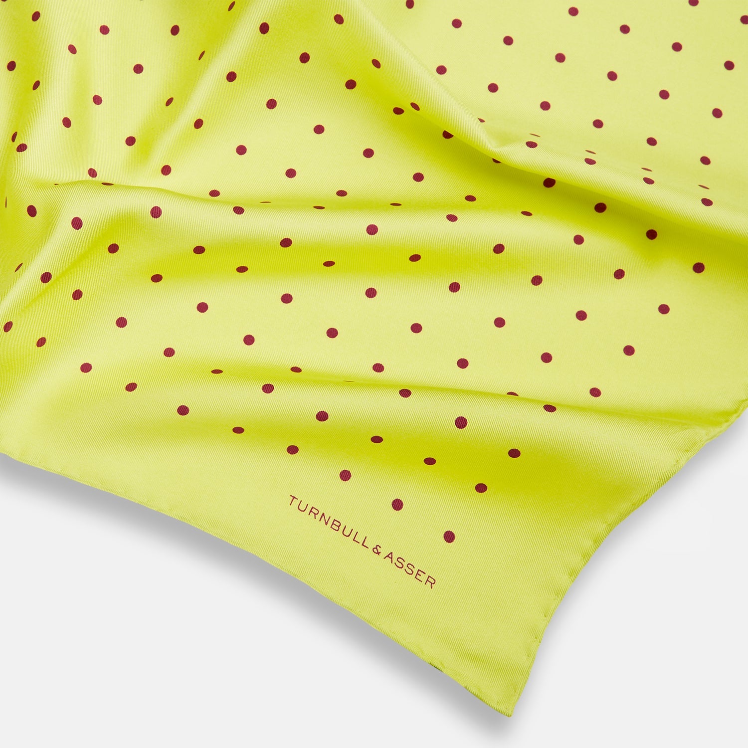 View 2 of product The Turnbull & Asser Chartreuse and Mauve Spot Silk Pocket Square features evenly spaced mauve dots and a branded corner—an ideal accessory to enhance your formal look.