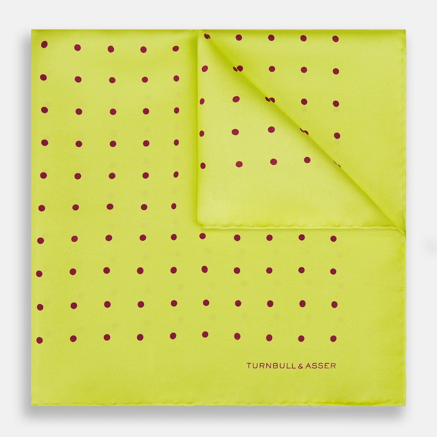 View 1 of product The Turnbull & Asser Chartreuse and Mauve Spot Silk Pocket Square features evenly spaced mauve dots and a branded corner—an ideal accessory to enhance your formal look.