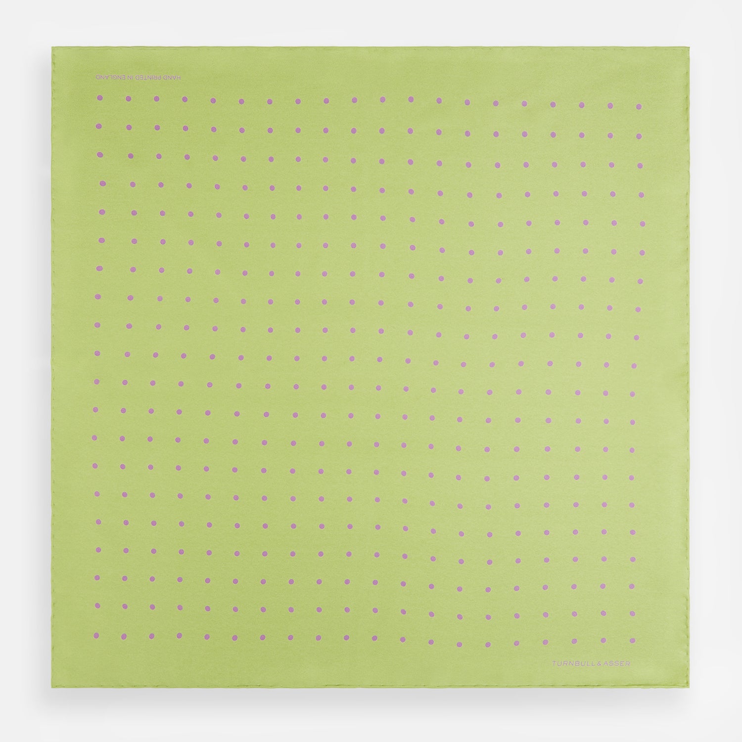 View 4 of product The Turnbull & Asser Melon Green and Lilac Spot Silk Pocket Square features evenly spaced lilac dots and the brand's name in one corner—a refined accessory for formal attire.