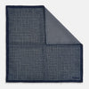 View 1 of product The Rosette Navy Pocket Square in Silk by Turnbull & Asser UK is a square, navy blue accessory featuring a small geometric pattern. Shown laid flat with one corner folded, it reveals a contrasting, finer motif on the reverse side. This elegant double-sided design offers versatile styling options for any occasion.