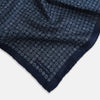 View 2 of product The Rosette Navy Pocket Square in Silk by Turnbull & Asser UK is a square, navy blue accessory featuring a small geometric pattern. Shown laid flat with one corner folded, it reveals a contrasting, finer motif on the reverse side. This elegant double-sided design offers versatile styling options for any occasion.