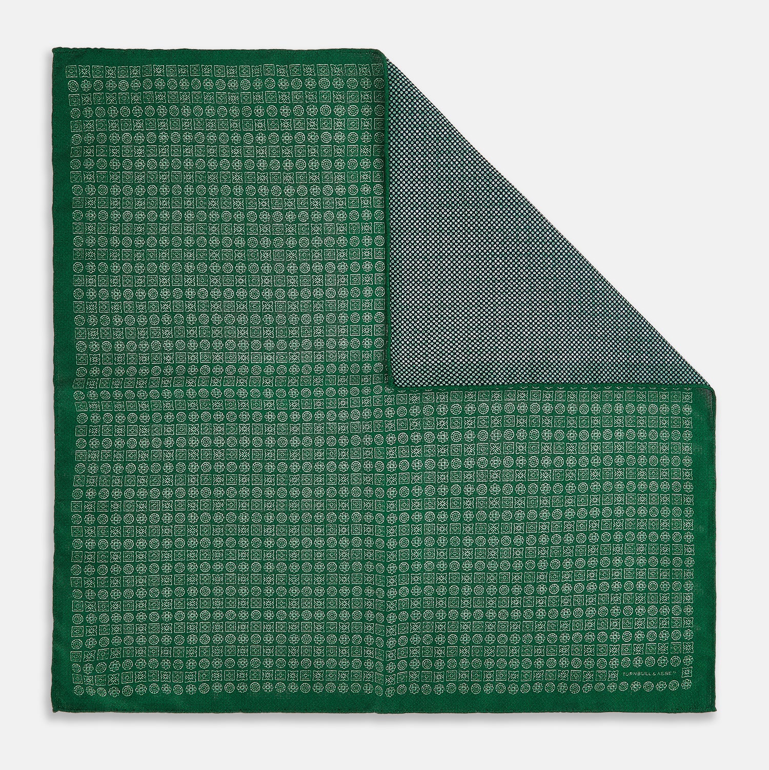 View 2 of product The Rosette Green Pocket Square in Silk by Turnbull & Asser UK features a small geometric medallion pattern and is shown folded to display a contrasting fine black-and-white design on the reverse side.