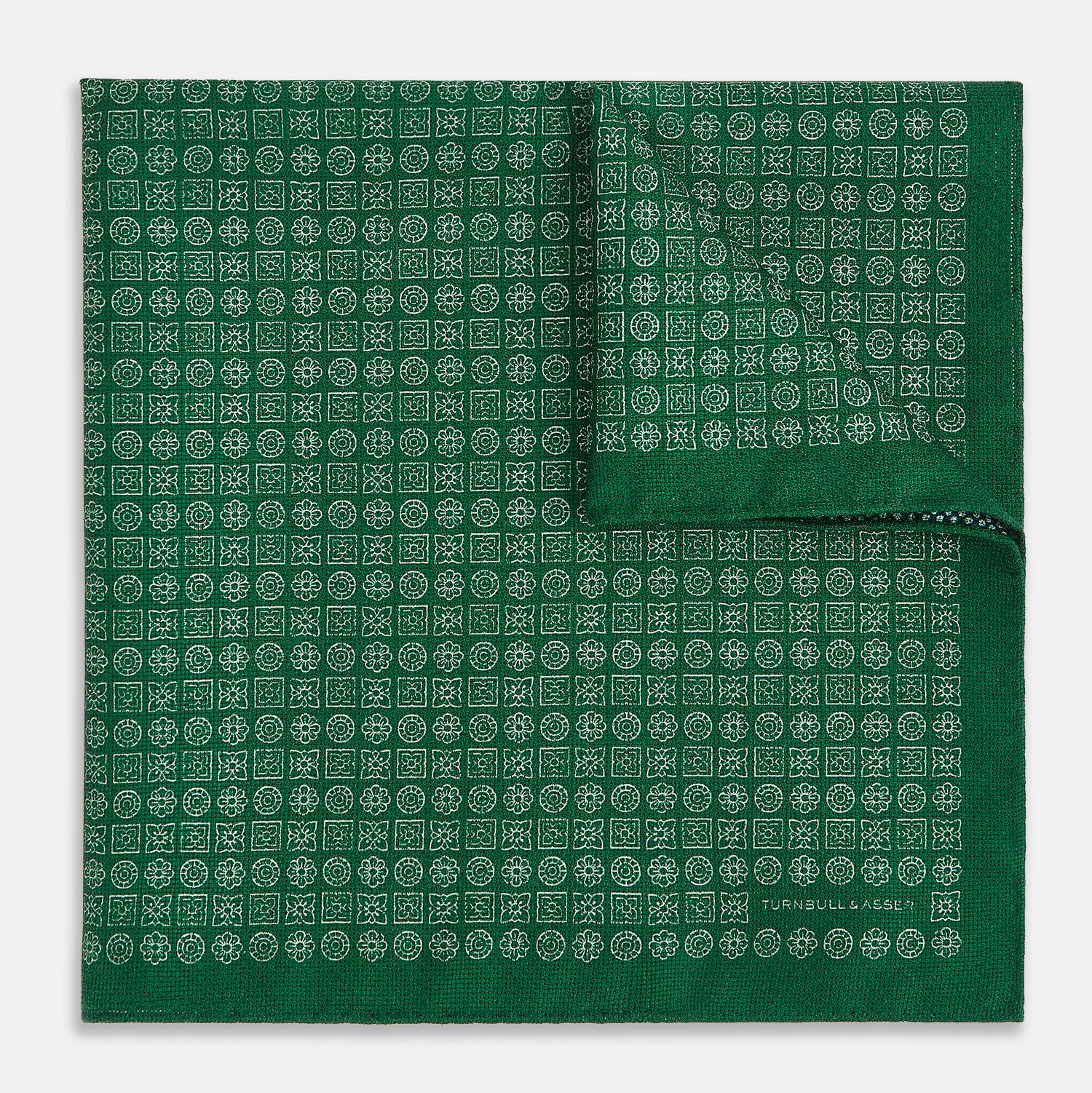 View 3 of product The Rosette Green Pocket Square in Silk by Turnbull & Asser UK features a small geometric medallion pattern and is shown folded to display a contrasting fine black-and-white design on the reverse side.