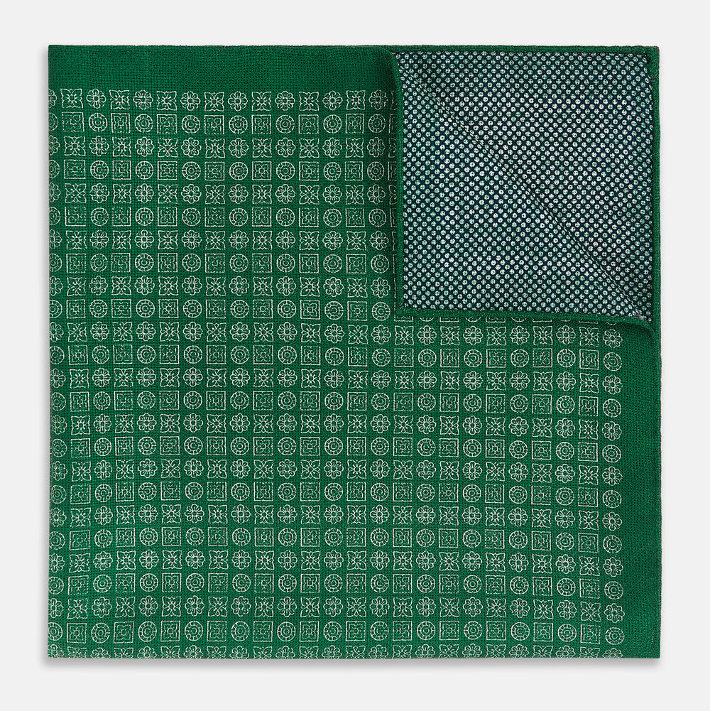 The Rosette Green Pocket Square in Silk by Turnbull & Asser UK features a small geometric medallion pattern and is shown folded to display a contrasting fine black-and-white design on the reverse side.