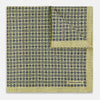 View 2 of product The Rosette Yellow Pocket Square in Silk by Turnbull & Asser UK features a square design with a yellow border, adorned with a grid of small black and white circles. One corner is neatly folded to reveal a reverse side in a refined black and white micro-checkered pattern, while subtle geometric medallions lend an added touch of elegance to the overall look.