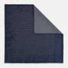 View 1 of product The Checked Blue Pocket Square in Silk by Turnbull & Asser UK features a navy base with a light blue grid pattern on one side and a refined dotted design on the other. This double-sided accessory is shown partially folded to elegantly showcase both distinctive patterns.
