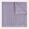 View 2 of product The Checked Lilac Pocket Square in Silk by Turnbull & Asser UK features a grid pattern in purple with a solid border, neatly folded to display its double-sided design and contrasting black and white dotted squares on the reverse side.