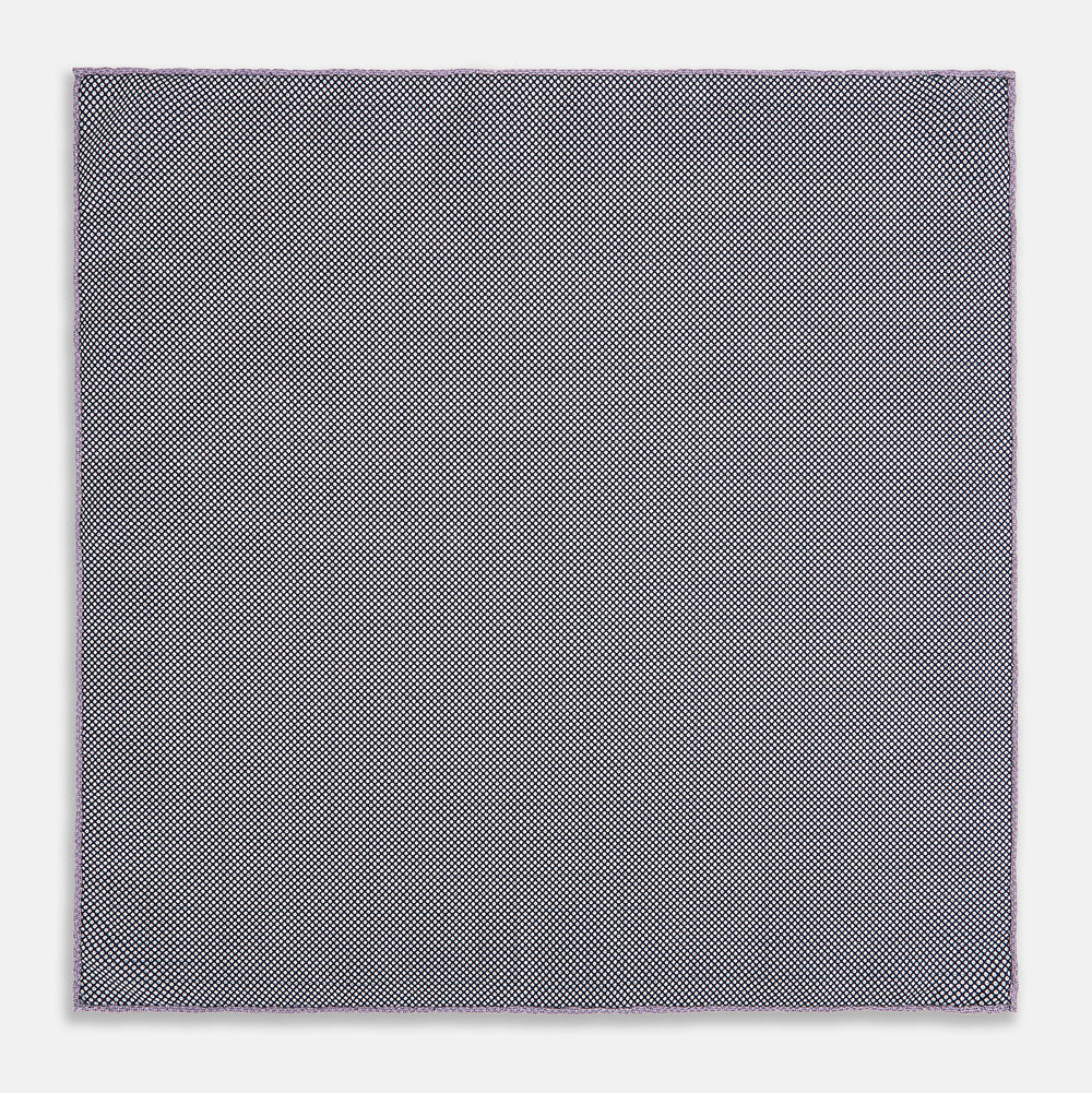 The Checked Lilac Pocket Square in Silk by Turnbull & Asser UK features a grid pattern in purple with a solid border, neatly folded to display its double-sided design and contrasting black and white dotted squares on the reverse side.