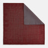 View 1 of product The Turnbull & Asser UK Checked Burgundy Pocket Square in Silk features a sophisticated burgundy hue with a subtle grid pattern. It's displayed folded at one corner to reveal a contrasting small checkered design on the reverse, showcasing its refined double-sided craftsmanship.