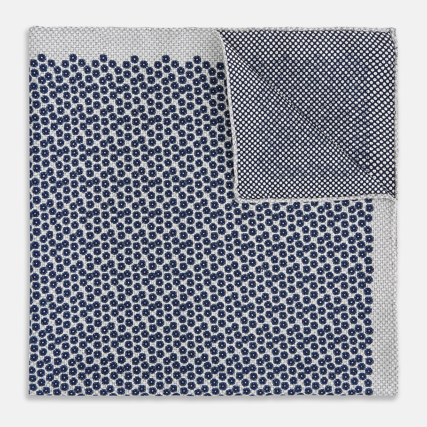 View 4 of product A square silk pocket square from Turnbull & Asser UK, featuring a subtle floral grey pattern; one corner is folded to reveal its double-sided design with a complementary pattern on the reverse side.