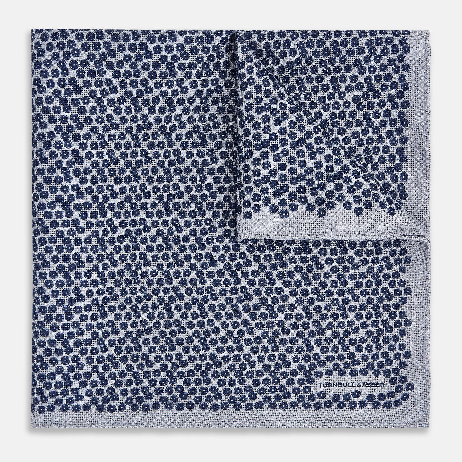 View 2 of product The Turnbull & Asser UK Floral Blue Pocket Square in Silk showcases a refined double-sided design, with a clustered dot pattern in blue and white on the front and a delicate fine dotted motif on the back. Presented with one corner elegantly folded, it exudes sophisticated style.
