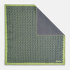 View 1 of product The Turnbull & Asser UK Floral Green Pocket Square in Silk is a square accessory featuring a blue floral pattern with a green border, partly folded at one corner to showcase its double-sided design, revealing a navy and light green dotted pattern on the reverse.