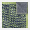 View 4 of product The Turnbull & Asser UK Floral Green Pocket Square in Silk is a square accessory featuring a blue floral pattern with a green border, partly folded at one corner to showcase its double-sided design, revealing a navy and light green dotted pattern on the reverse.