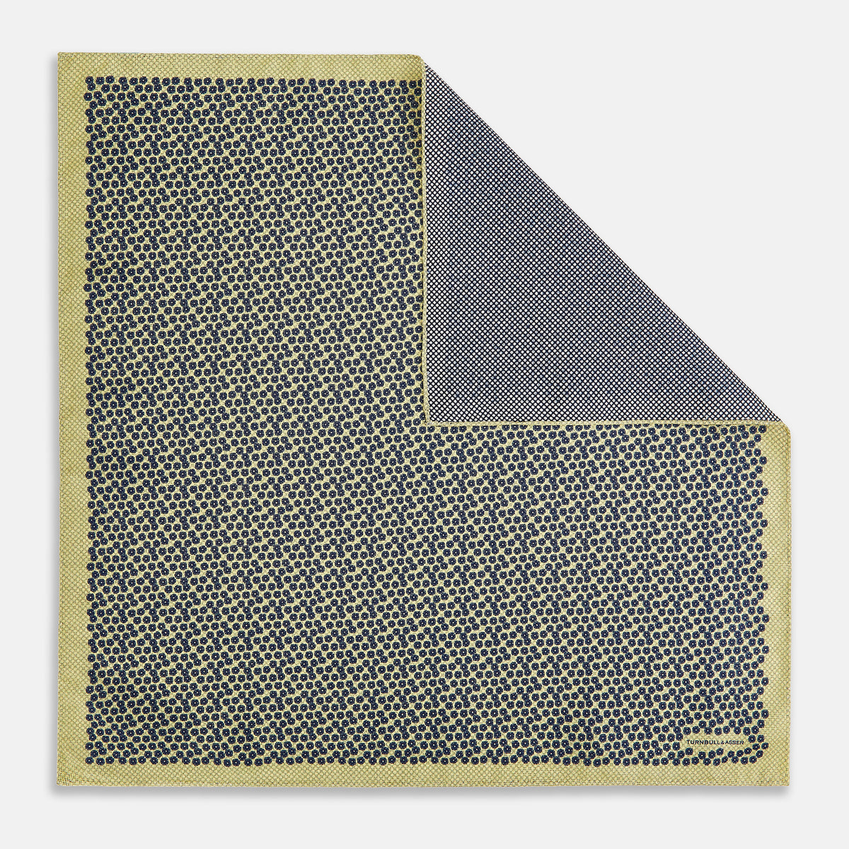 View 3 of product Introducing the Floral Yellow Pocket Square in Silk by Turnbull & Asser UK—a sophisticated square accessory featuring a vibrant yellow border and a black-and-white geometric dot pattern. One corner is tastefully folded to reveal its double-sided design, showcasing a smaller, denser dot motif on the reverse. Perfect for adding a modern touch of flair to any outfit or setting.