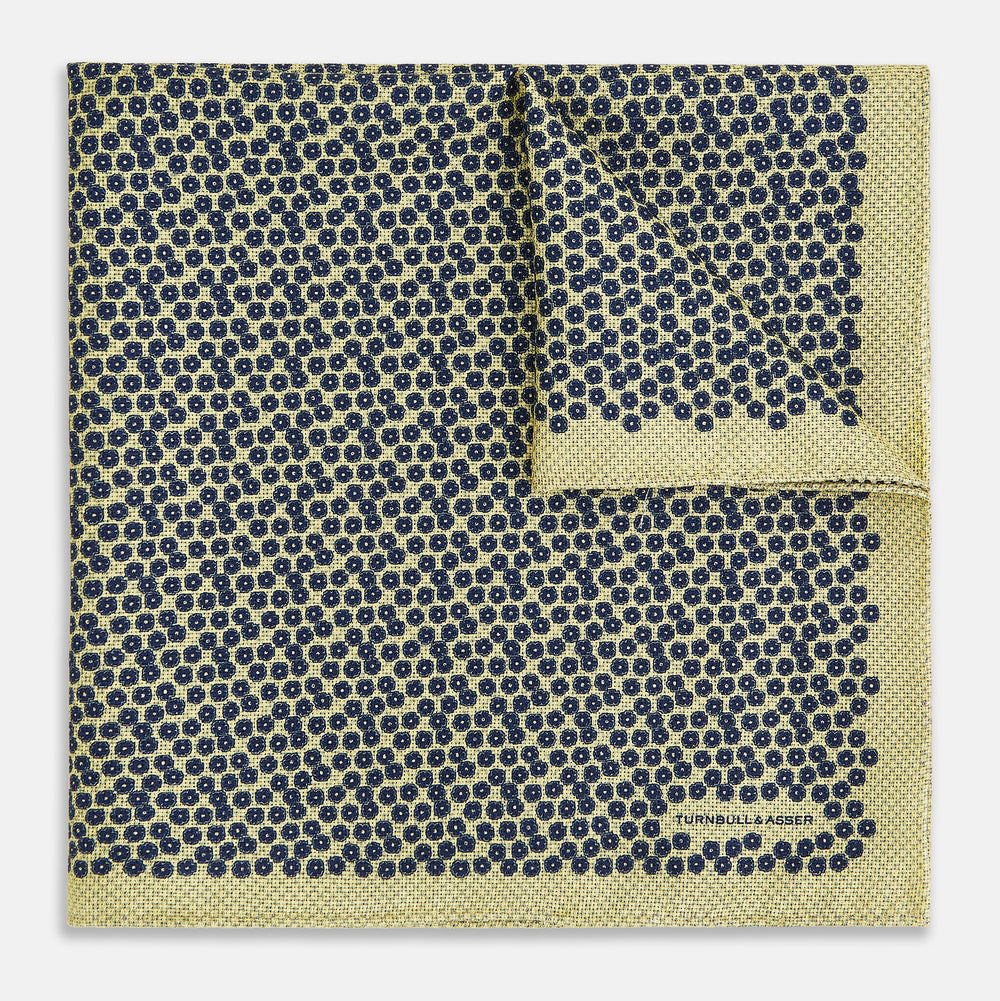Introducing the Floral Yellow Pocket Square in Silk by Turnbull & Asser UK—a sophisticated square accessory featuring a vibrant yellow border and a black-and-white geometric dot pattern. One corner is tastefully folded to reveal its double-sided design, showcasing a smaller, denser dot motif on the reverse. Perfect for adding a modern touch of flair to any outfit or setting.