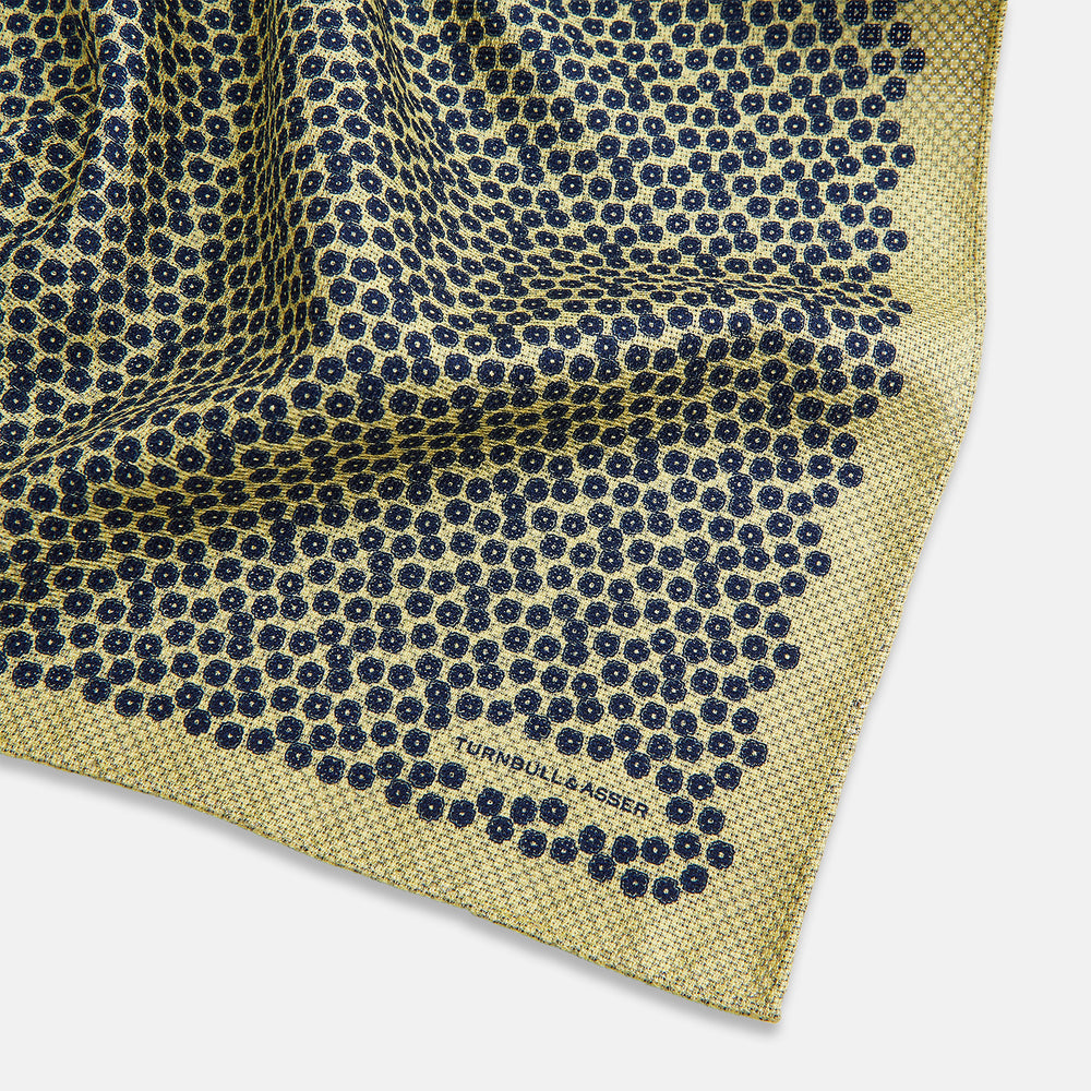 Introducing the Floral Yellow Pocket Square in Silk by Turnbull & Asser UK—a sophisticated square accessory featuring a vibrant yellow border and a black-and-white geometric dot pattern. One corner is tastefully folded to reveal its double-sided design, showcasing a smaller, denser dot motif on the reverse. Perfect for adding a modern touch of flair to any outfit or setting.