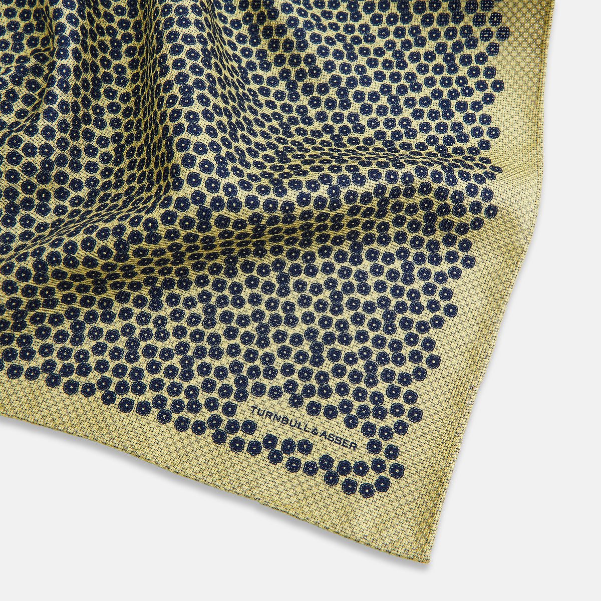 View 2 of product Introducing the Floral Yellow Pocket Square in Silk by Turnbull & Asser UK—a sophisticated square accessory featuring a vibrant yellow border and a black-and-white geometric dot pattern. One corner is tastefully folded to reveal its double-sided design, showcasing a smaller, denser dot motif on the reverse. Perfect for adding a modern touch of flair to any outfit or setting.