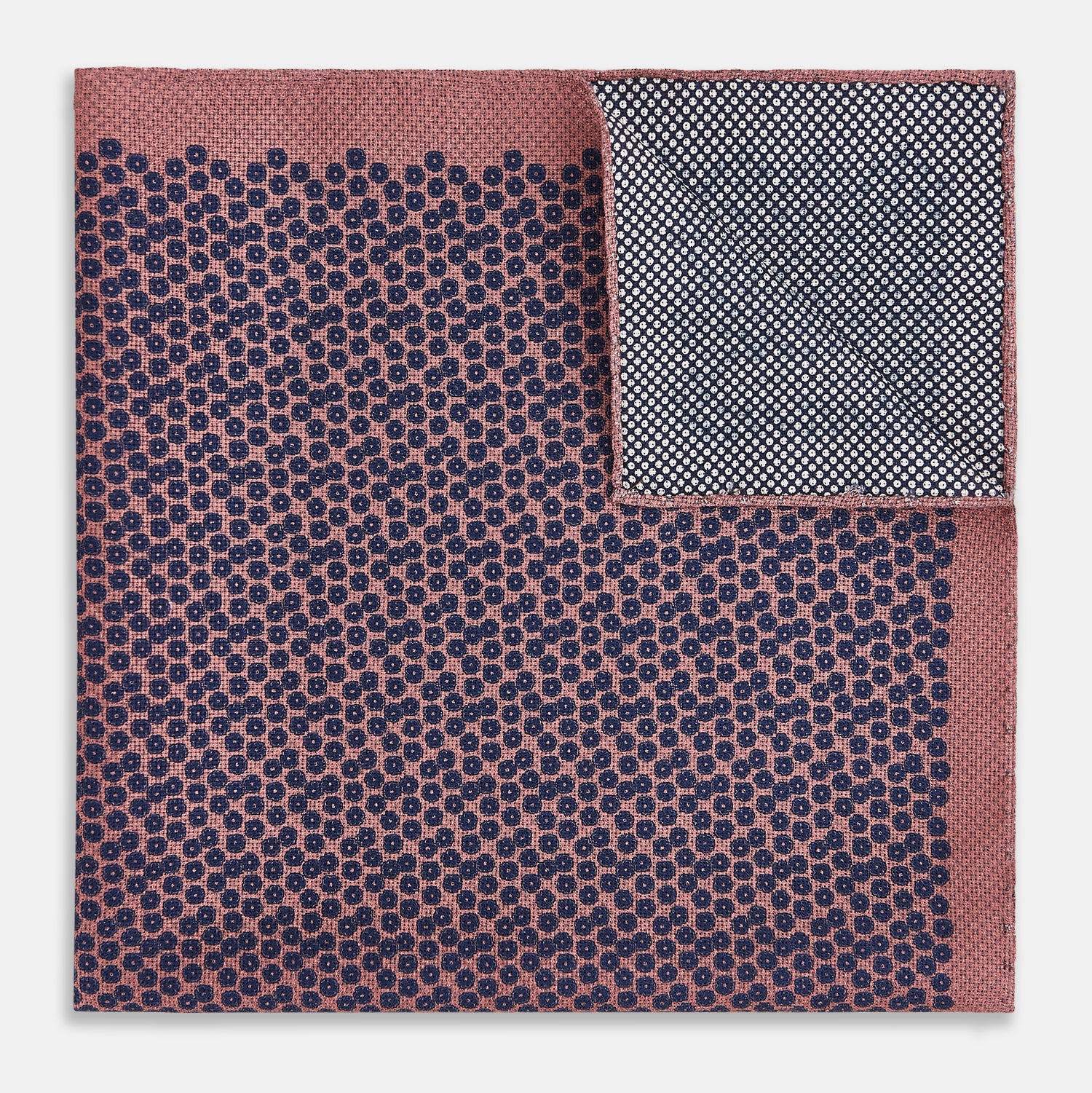 View 4 of product The Floral Pink Pocket Square in Silk by Turnbull & Asser UK showcases a refined pattern with a pink floral design and a contrasting border. The top right corner is elegantly folded to reveal the reverse side’s complementary blue and white dotted motif, emphasizing its double-sided versatility.