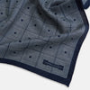 View 3 of product Introducing the Geometric Navy Tile Pocket Square in Silk by Turnbull & Asser UK—a folded navy and white accessory showcasing a double-sided design, with one side featuring concentric squares that form a striking geometric pattern and the other adorned with an elegant small dot motif.